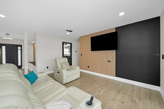 living room featuring light wood-type flooring, an accent wall, baseboards, and recessed lighting