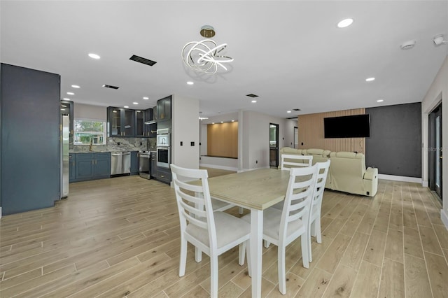 dining area with light wood-type flooring, baseboards, a notable chandelier, and recessed lighting