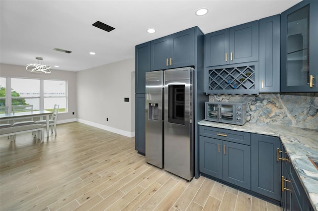 kitchen featuring light wood finished floors, blue cabinetry, stainless steel refrigerator with ice dispenser, backsplash, and recessed lighting