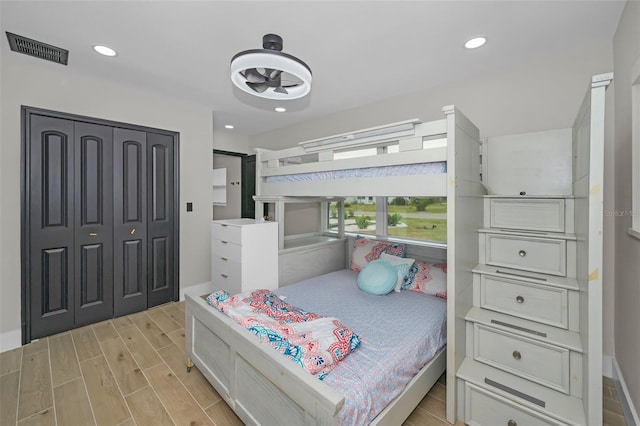 bedroom with wood finish floors, a closet, visible vents, and recessed lighting