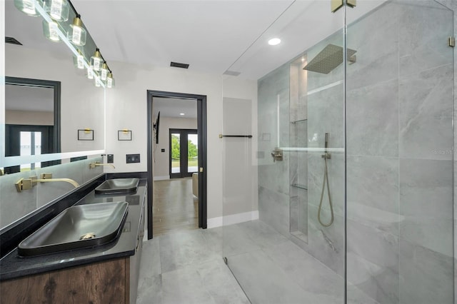 bathroom with french doors, walk in shower, a sink, and baseboards