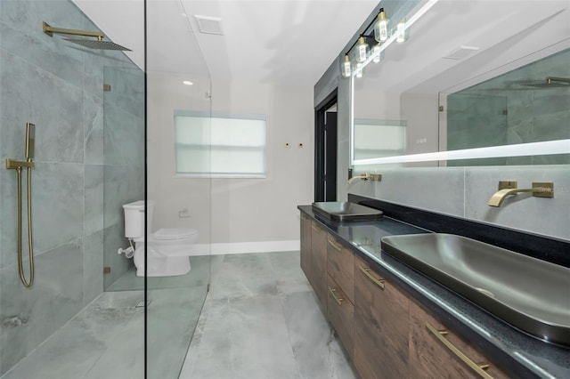 full bath featuring a sink, a tile shower, toilet, and double vanity