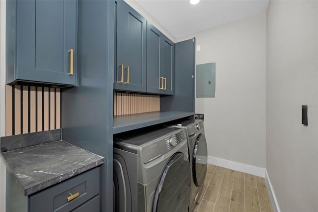 washroom with baseboards, light wood-style floors, independent washer and dryer, cabinet space, and electric panel