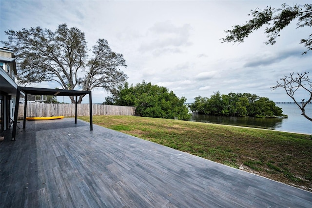 deck featuring a water view, fence, and a lawn