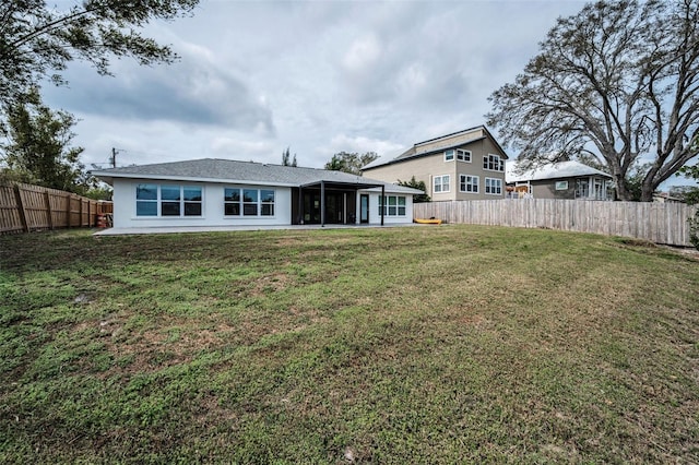 back of property with a lawn, a fenced backyard, and a sunroom