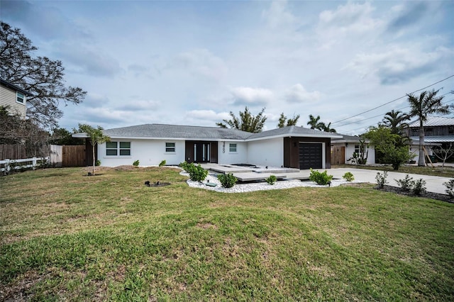 view of front of property featuring driveway, a garage, fence, a front yard, and stucco siding