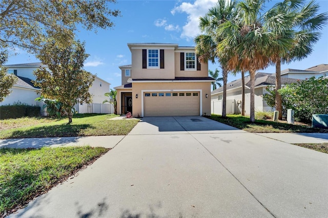 traditional home featuring driveway, stucco siding, an attached garage, fence, and a front yard