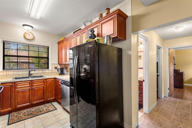 kitchen featuring a sink, a textured ceiling, black fridge, light tile patterned floors, and stainless steel dishwasher