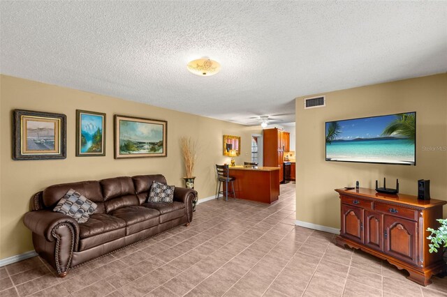 living area featuring light tile patterned floors, baseboards, visible vents, and a textured ceiling