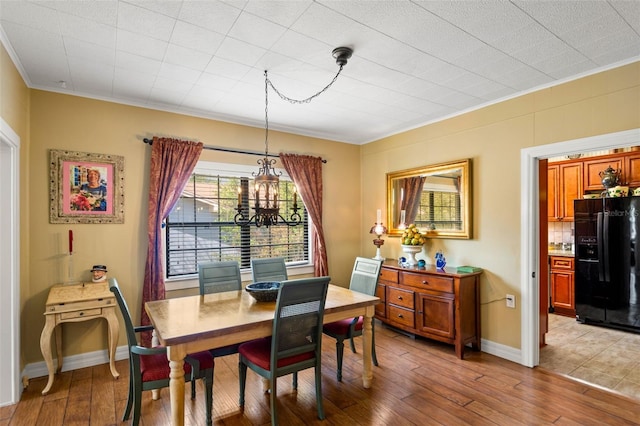 dining area with light wood-type flooring, baseboards, ornamental molding, and a notable chandelier