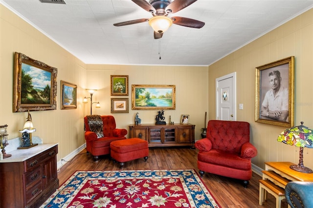 sitting room featuring wood finished floors, ornamental molding, visible vents, ceiling fan, and baseboards
