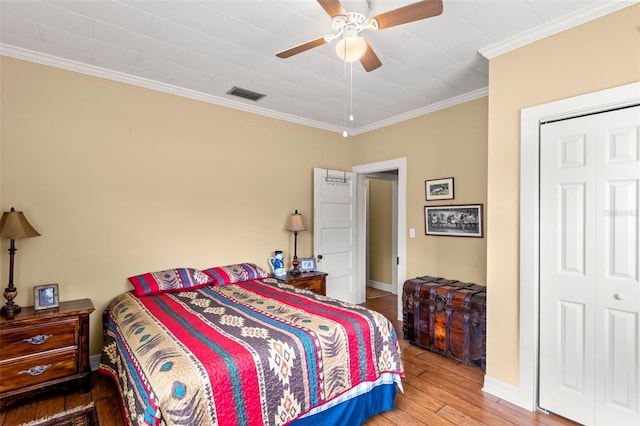 bedroom with baseboards, hardwood / wood-style floors, crown molding, and visible vents