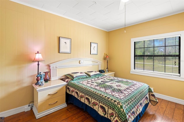 bedroom with ornamental molding, hardwood / wood-style floors, and baseboards
