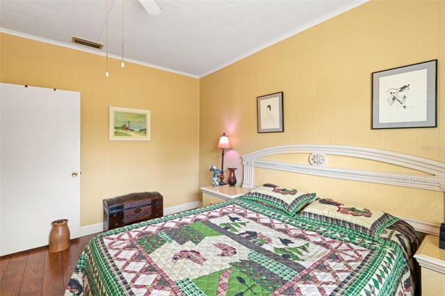 bedroom featuring ornamental molding, hardwood / wood-style flooring, baseboards, and visible vents