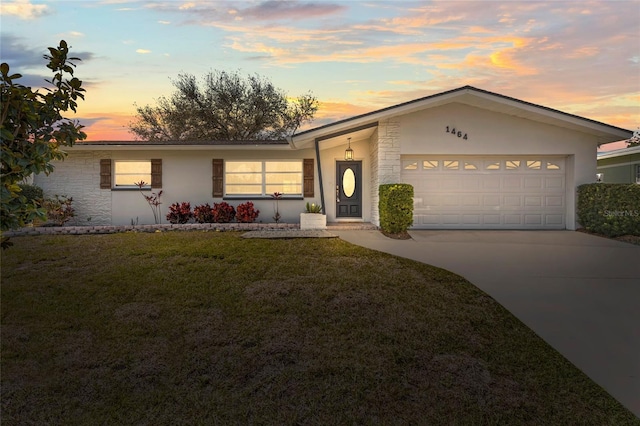 view of front facade featuring a garage, a yard, driveway, and stucco siding