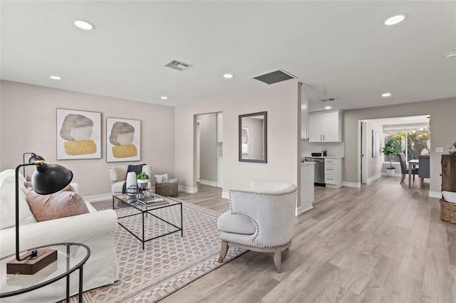 living room with recessed lighting, visible vents, and light wood-style flooring