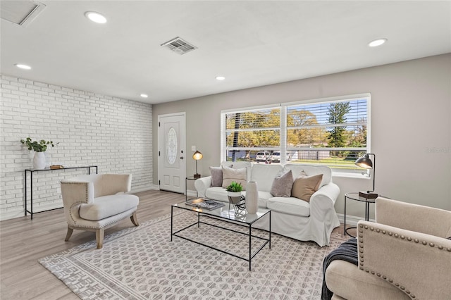 living room with recessed lighting, brick wall, visible vents, baseboards, and light wood-type flooring