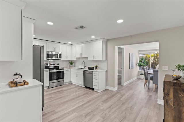 kitchen featuring a sink, visible vents, appliances with stainless steel finishes, light wood-type flooring, and decorative backsplash