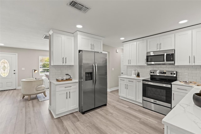 kitchen with stainless steel appliances, visible vents, and light wood finished floors