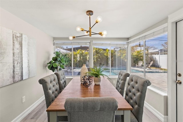 dining room with light wood-style floors, plenty of natural light, baseboards, and a notable chandelier