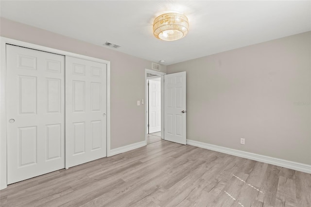 unfurnished bedroom featuring light wood-style floors, a closet, visible vents, and baseboards