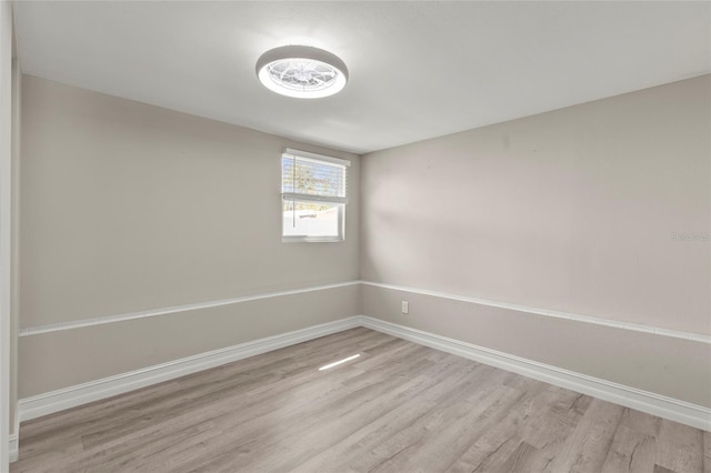 spare room with baseboards and light wood-style floors