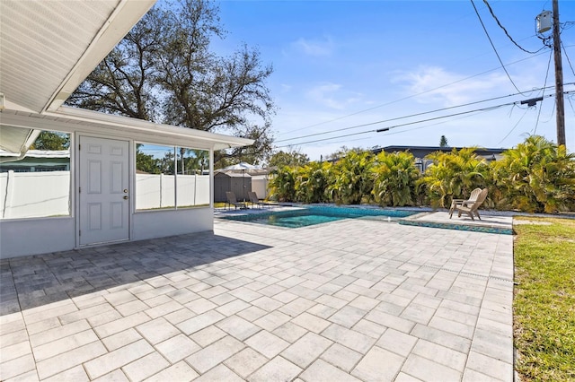 outdoor pool featuring an outbuilding, a patio, a storage shed, and fence