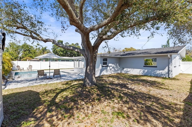 rear view of house featuring a patio area, a fenced backyard, a fenced in pool, and stucco siding