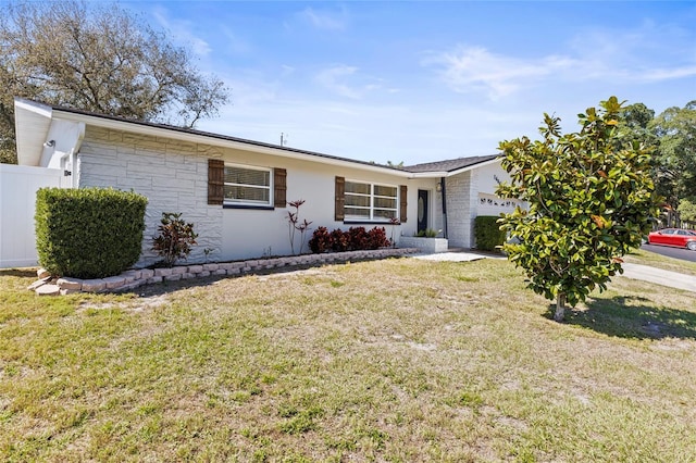 single story home featuring stone siding, an attached garage, fence, and a front yard