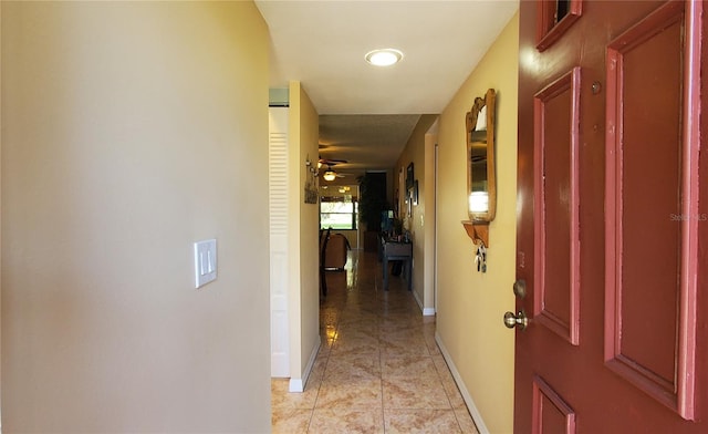 corridor featuring light tile patterned floors and baseboards