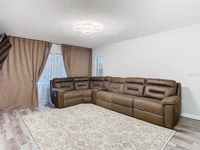 living area featuring baseboards, a textured ceiling, and light wood finished floors