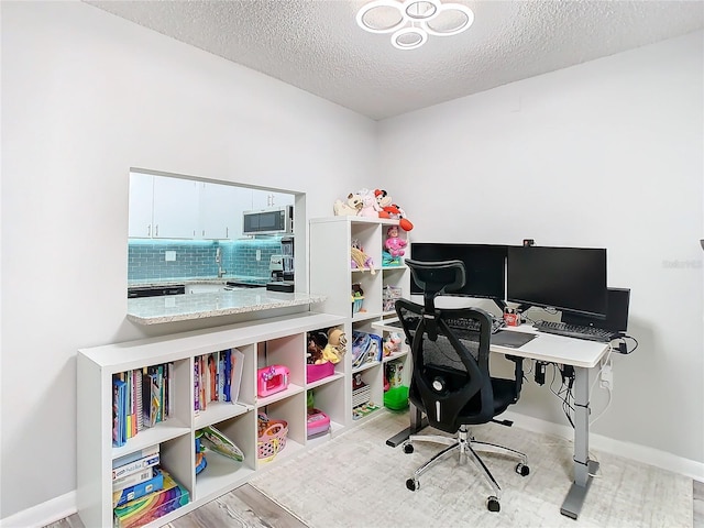 office space with a textured ceiling, light wood-style flooring, and baseboards