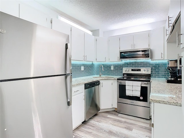 kitchen featuring white cabinets, light wood-style flooring, stainless steel appliances, and a sink