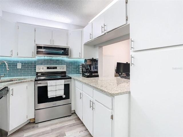 kitchen featuring light wood-style floors, white cabinetry, stainless steel appliances, and a sink