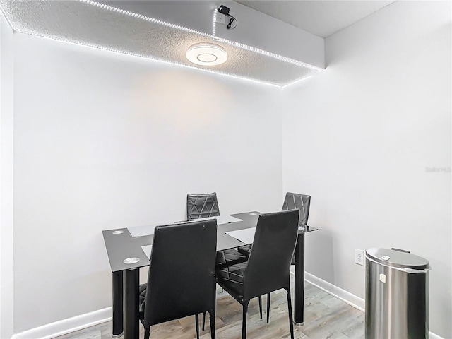 dining space with baseboards and wood finished floors