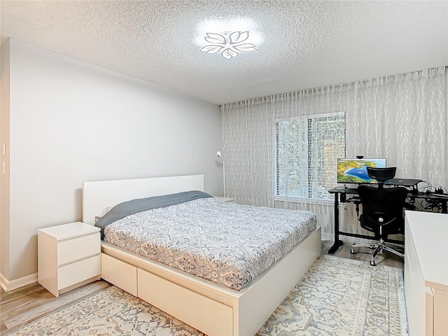 bedroom with light wood-style flooring and a textured ceiling