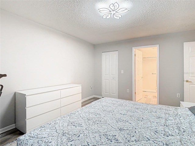 bedroom featuring dark wood-type flooring, a textured ceiling, baseboards, and ensuite bathroom