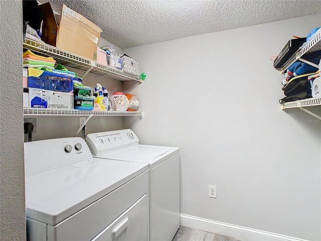 washroom featuring laundry area, baseboards, light wood-style flooring, a textured ceiling, and washer and dryer