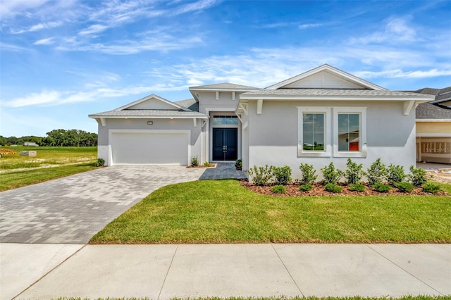 view of front of home featuring roof with shingles, an attached garage, decorative driveway, a front yard, and stucco siding