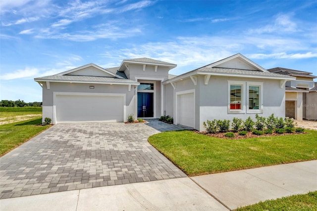 view of front of home featuring a front yard, decorative driveway, and an attached garage