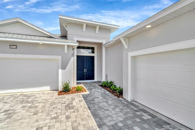 10714 Torchwood Sea Way, San Antonio, FL 33576 - view of exterior entry featuring an attached garage, decorative driveway, and stucco siding