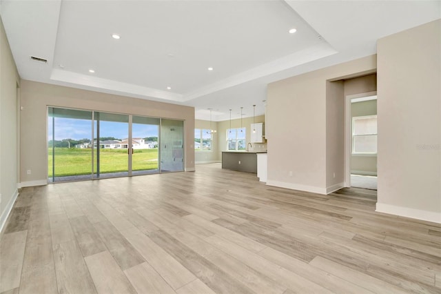 10714 Torchwood Sea Way, San Antonio, FL 33576 - unfurnished living room featuring light wood-style floors, visible vents, and a raised ceiling