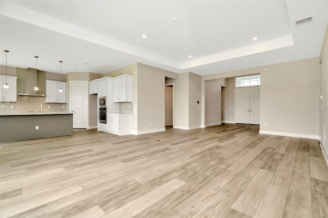 10714 Torchwood Sea Way, San Antonio, FL 33576 - unfurnished living room with a raised ceiling, visible vents, baseboards, and light wood finished floors