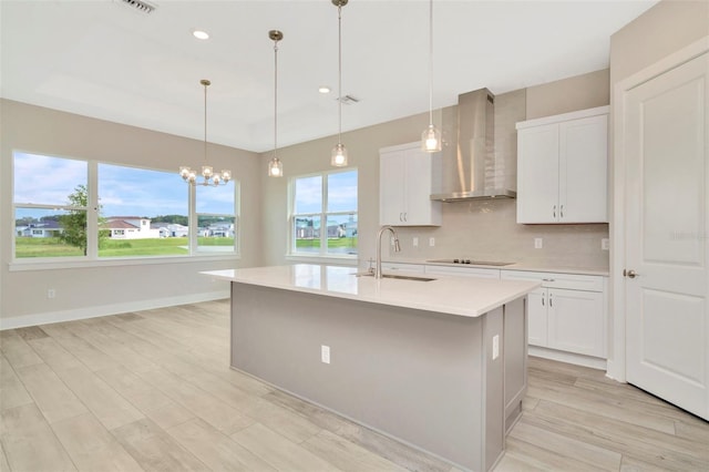10714 Torchwood Sea Way, San Antonio, FL 33576 - kitchen with light countertops, a kitchen island with sink, a sink, wall chimney range hood, and white cabinetry