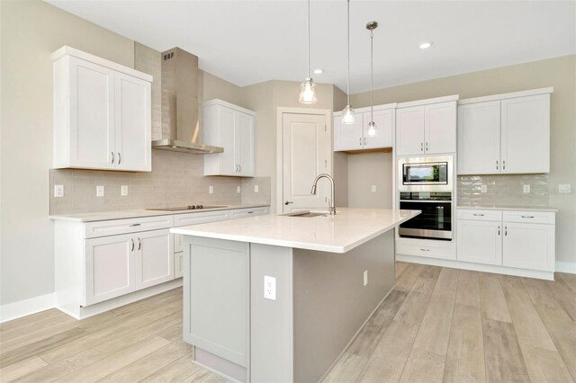 10714 Torchwood Sea Way, San Antonio, FL 33576 - kitchen with an island with sink, wall chimney exhaust hood, stainless steel appliances, light countertops, and a sink