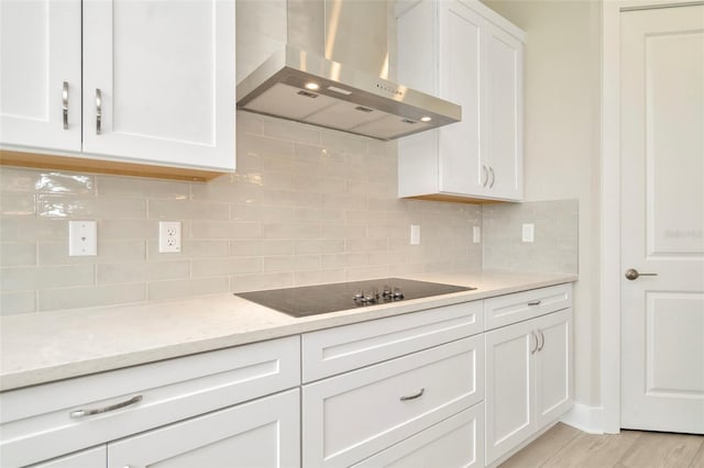 10714 Torchwood Sea Way, San Antonio, FL 33576 - kitchen featuring backsplash, white cabinetry, island range hood, light stone countertops, and black electric cooktop