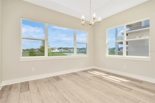 10714 Torchwood Sea Way, San Antonio, FL 33576 - unfurnished room with light wood-type flooring, baseboards, and a notable chandelier