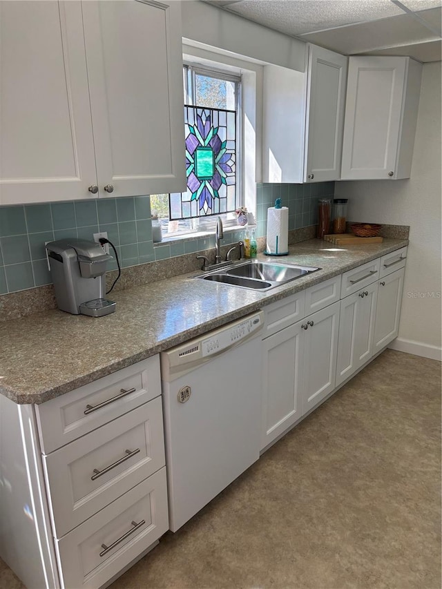 kitchen featuring tasteful backsplash, baseboards, white dishwasher, white cabinetry, and a sink