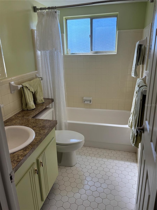 full bath with toilet, vanity, tile walls, tile patterned floors, and shower / bath combo