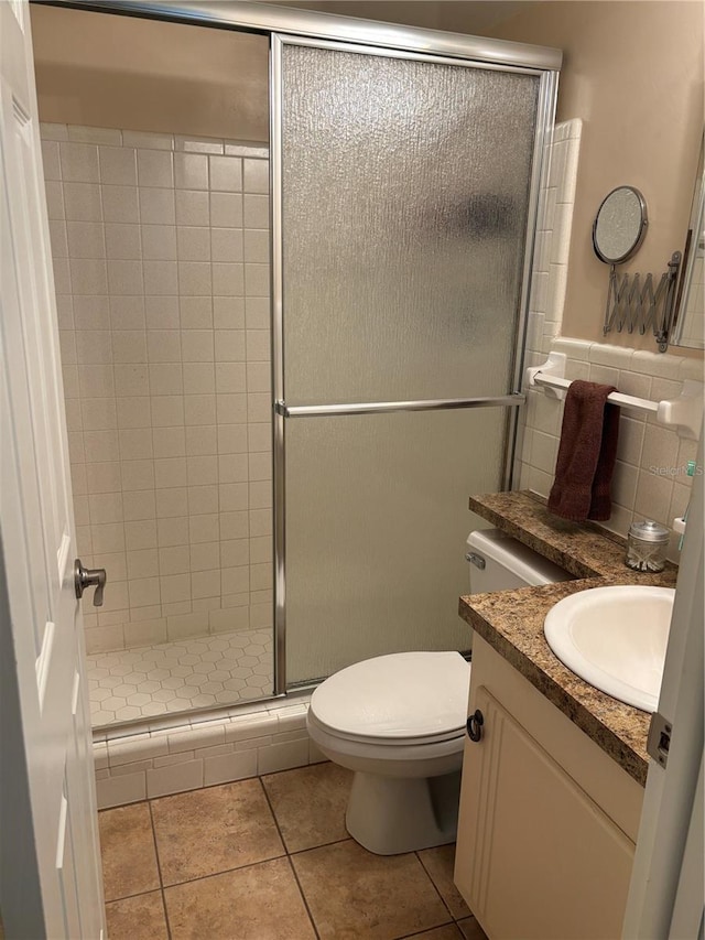 full bathroom featuring tile walls, toilet, a shower stall, vanity, and tile patterned floors